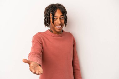 Beyaz arka planda izole edilmiş genç Afro-Amerikalı adam selamlaşma jesti olarak kameraya uzanıyor..
