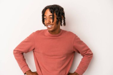 Beyaz arka planda izole edilmiş genç Afrikalı Amerikalı adam mutlu bir şekilde gülüyor ve ellerini karnının üstünde tutarak eğleniyor..