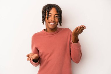 Beyaz arka planda izole edilmiş genç Afrikalı Amerikalı adam kollarıyla ölçek oluşturuyor, mutlu ve kendinden emin hissediyor..