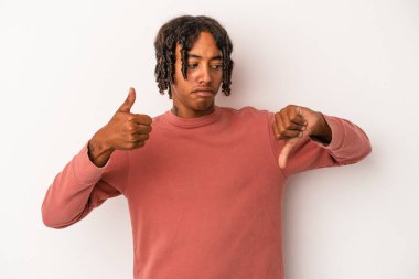 Beyaz arka planda izole edilmiş genç Afro-Amerikalı adam baş parmağını kaldırıyor ve baş parmağını aşağı gösteriyor, zor seçim konsepti