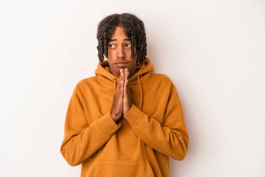 Genç Afrikalı Amerikalı adam beyaz arka planda izole edilmiş dua ediyor, bağlılık gösteriyor, dindar biri ilahi ilham arıyor..
