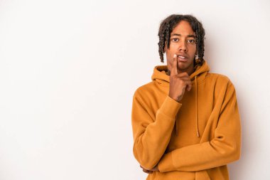 Beyaz arka planda izole edilmiş genç Afrikalı Amerikalı şüpheli ve şüpheci bir ifadeyle yana bakıyor..