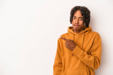 Beyaz arka planda izole edilmiş genç Afrikalı Amerikalı adam gülümsüyor ve boş alanda bir şeyler gösteriyor..