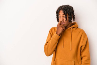 Beyaz arka planda izole edilmiş genç Afrikalı Amerikalı bir şey hakkında rahatça düşünüyor ve bir fotokopi odasına bakıyor..