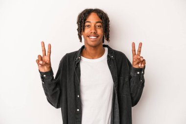 Beyaz arka planda izole edilmiş genç bir Afrikalı Amerikalı zafer işareti gösteriyor ve gülümsüyor..