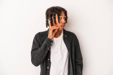 Genç Afrikalı Amerikalı adam beyaz arka planda izole edilmiş bir şekilde bir dedikoduyu dinlemeye çalışıyor..