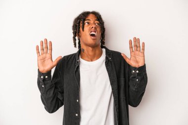 Genç Afrikalı Amerikalı adam beyaz arka planda izole edilmiş gökyüzüne haykırıyor, yukarı bakıyor, hayal kırıklığına uğramış..