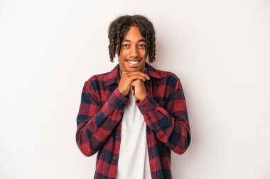 Beyaz arka planda izole edilmiş genç Afrikalı Amerikalı ellerini çenesinin altında tutuyor ve mutlu bir şekilde yan tarafa bakıyor..