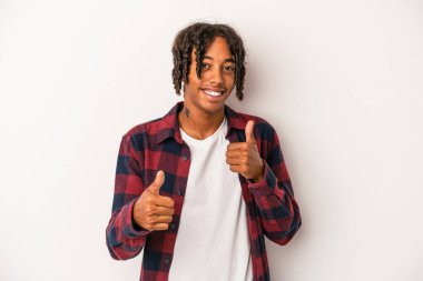 Genç Afrikalı Amerikalı adam beyaz arka planda izole edilmiş. Baş parmağını kaldırıyor, gülümsüyor ve kendinden emin..