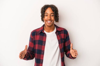 Beyaz arka planda izole edilmiş genç Afrikalı Amerikalı iki eliyle bir şey tutuyor, ürün sunumu..