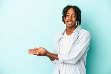 Genç Afro-Amerikalı bir adam mavi arka planda izole edilmiş. Elinde bir fotokopi alanı var..