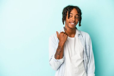 Genç Afrikalı Amerikalı adam mavi arka plan noktalarında izole edilmiş, başparmak uzakta, gülüyor ve kaygısız..