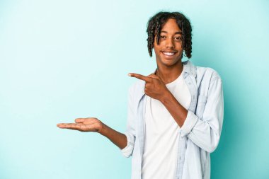 Genç Afro-Amerikan adam mavi arka planda izole edilmiş. Elinde bir fotokopi alanı tutarken heyecanlı..