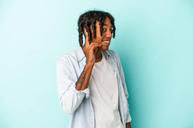 Genç Afrikalı Amerikalı bir adam mavi arka planda izole edilmiş bir şekilde bir dedikoduyu dinlemeye çalışıyor..