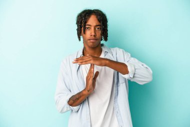 Genç Afrikalı Amerikalı bir adam mavi arka planda izole edilmiş..