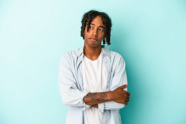 Genç Afrikalı Amerikalı adam mavi arka planda izole edilmiş hedeflerine ve amaçlarına ulaşma hayali kuruyor.