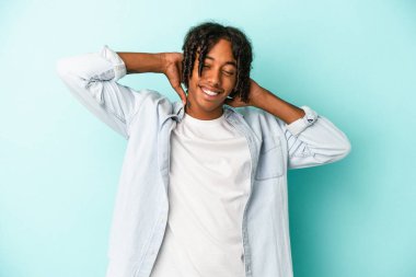 Genç Afrikalı Amerikalı adam mavi arka planda izole edilmiş kollarını açmış, rahat bir pozisyonda..