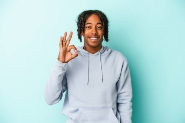 Genç Afrikalı Amerikalı adam mavi arka planda izole edilmiş neşeli ve kendinden emin..
