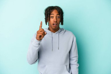 Genç Afrikalı Amerikalı bir adam mavi arka planda izole edilmiş. Bir fikri, ilham verici bir konsepti var..