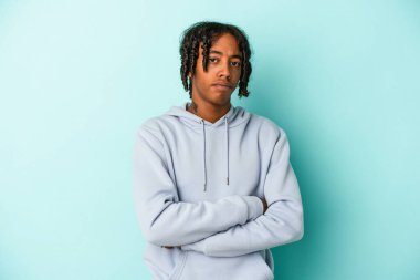 Genç Afrikalı Amerikalı bir adam mavi arka planda izole edilmiş şüpheli, belirsiz, seni inceliyor..