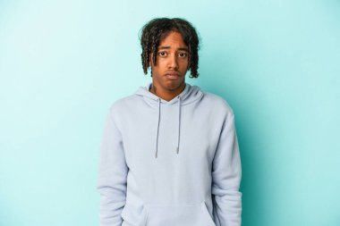 Mavi arka planda izole edilmiş genç Afrikalı Amerikalı adamın yanakları şişer, yorgun bir ifadesi vardır. Yüz ifadesi kavramı.