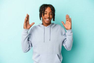 Genç Afrikalı Amerikalı adam mavi arka planda izole edilmiş neşeli bir şekilde gülüyor. Mutluluk kavramı.