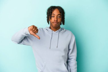 Genç Afro-Amerikalı adam mavi arka planda izole edilmiş, baş parmağını aşağı gösteren, hayal kırıklığı konsepti.