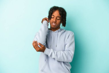 Genç Afrikalı Amerikalı adam mavi arka planda izole edilmiş dirsek masajı yapıyor, kötü bir hareketin ardından acı çekiyor..
