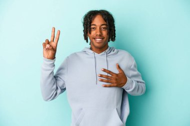 Genç Afrikalı Amerikalı adam mavi arka planda izole edilmiş bir şekilde yemin ediyor, elini göğsüne koyuyor..