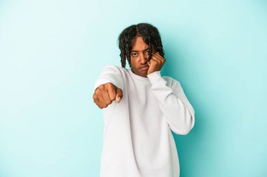 Genç Afrikalı Amerikalı bir adam mavi arka planda izole edilmiş. Bir tartışma yüzünden yumruk, öfke ve kavga atıyor..