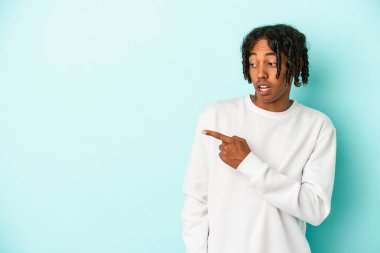 Genç Afrikalı Amerikalı adam mavi arka plan noktalarında izole edilmiş, başparmak uzakta, gülüyor ve kaygısız..