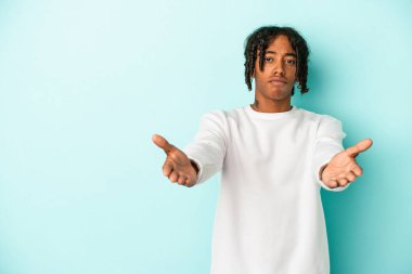 Genç Afrikalı Amerikalı adam mavi arka planda izole edilmiş dudaklarını kıvırıyor ve hava öpücüğü göndermek için avuç içi tutuyor..