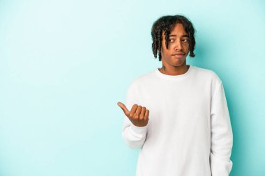 Mavi arka planda izole edilmiş genç Afro-Amerikalı adam işaret parmağıyla fotokopi alanını işaret ederek şok oldu..