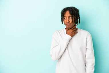 Genç Afrikalı Amerikalı adam mavi arka planda izole edilmiş kafasının arkasına dokunuyor, düşünüyor ve bir seçim yapıyor..