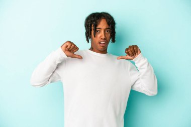 Mavi arka planda izole edilmiş genç bir Afrikalı Amerikalı gururlu ve kendinden emin hissediyor..