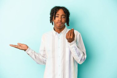 Genç Afrikalı Amerikalı bir adam mavi arka planda izole edilmiş. Bu da parasız olduğunu gösteriyor..