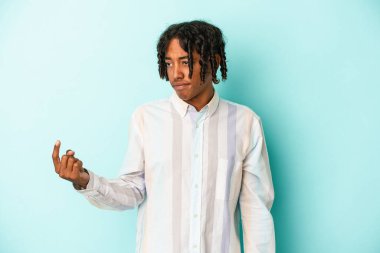 Genç Afro-Amerikalı adam mavi arka planda izole edilmiş, sanki seni davet ediyormuş gibi parmağıyla işaret ediyor..