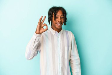 Genç Afrikalı Amerikalı adam mavi arka planda izole edilmiş neşeli ve kendinden emin..