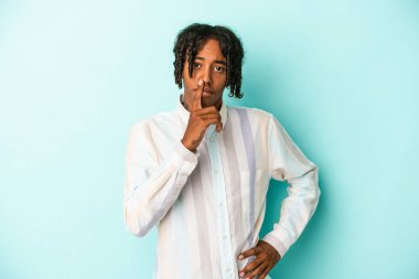 Genç Afrikalı Amerikalı bir adam mavi arka planda izole edilmiş bir şekilde sır saklıyor ya da sessizlik istiyor..