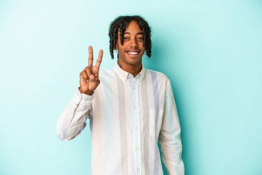 Genç Afrikalı Amerikalı adam mavi arka planda izole edilmiş. İki numarayı parmaklarıyla gösteriyor..