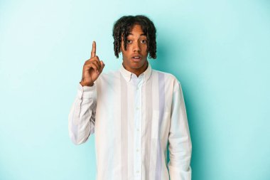 Genç Afrikalı Amerikalı bir adam mavi arka planda izole edilmiş. Harika bir fikri var, yaratıcılık kavramı..