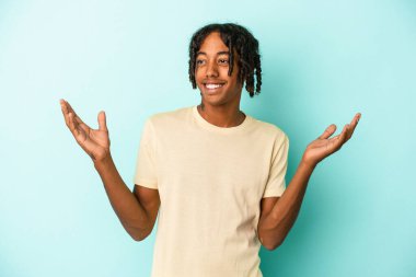 Genç Afrikalı Amerikalı adam mavi arka planda izole edilmiş neşeli bir şekilde gülüyor. Mutluluk kavramı.