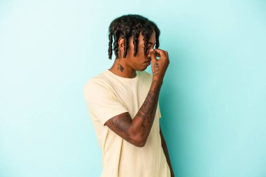 Genç Afrikalı Amerikalı bir adam mavi arka planda izole edilmiş, başı ağrıyor, yüzüne dokunuyor..