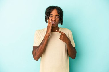 Genç Afrikalı Amerikalı bir adam mavi arka planda izole edilmiş güçlü bir diş ağrısı ve azı dişi ağrısı var..