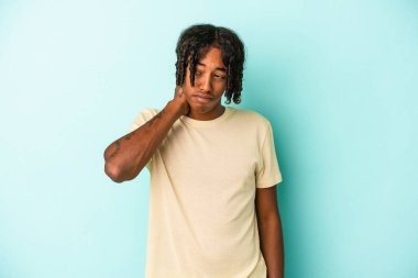 Genç Afrikalı Amerikalı erkek mavi arka planda izole edilmiş. Stres yüzünden boynu ağrıyor, masaj yapıyor ve elle dokunuyor..