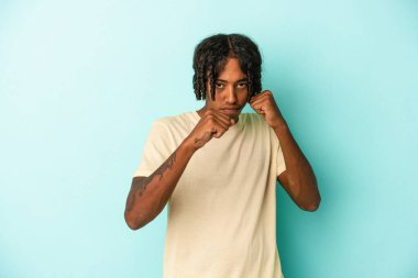 Genç Afrikalı Amerikalı bir adam mavi arka planda izole edilmiş. Bir tartışma yüzünden yumruk, öfke ve kavga atıyor..