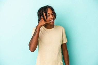 Genç Afrikalı Amerikalı bir adam mavi arka planda izole edilmiş, parmakları olan bir cep telefonu hareketi gösteriyor..