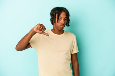 Genç Afro-Amerikan bir adam mavi arka planda izole edilmiş, hoşlanmadığı bir jest gösteriyor, başparmakları aşağıda. Anlaşmazlık konsepti.