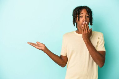 Mavi arka planda izole edilmiş genç Afro-Amerikalı adam, avuç içinin fotokopi alanından etkilenmiş..