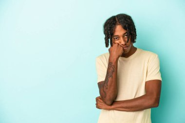 Mavi arka planda izole edilmiş genç Afrikalı Amerikalı üzgün ve dalgın bir şekilde fotokopi odasına bakıyor..